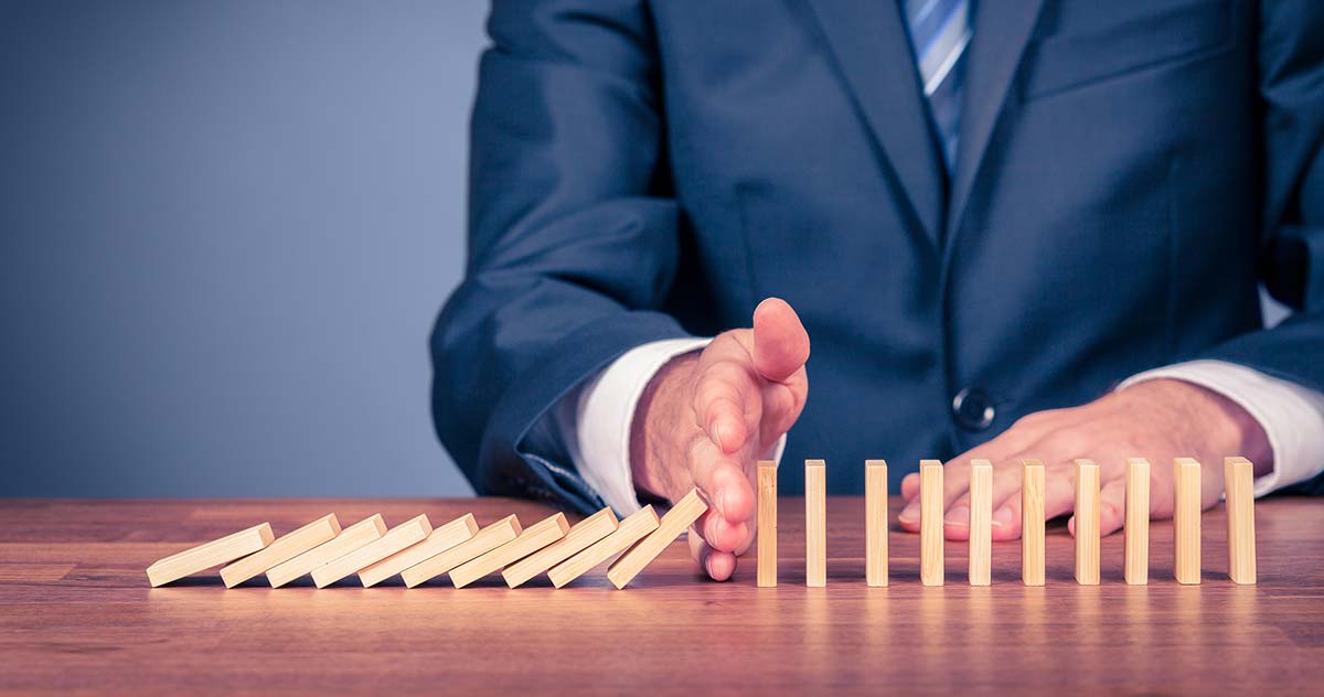 immagine di un uomo d'affari che interrompe l'effetto domino con una mano